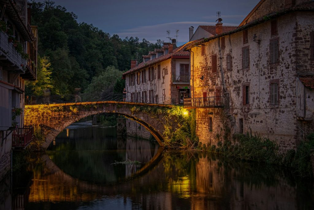 a stone bridge over a river next to a row of buildings